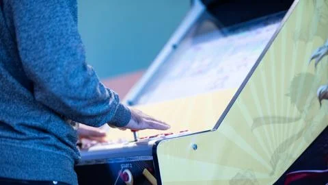 Man playing a classic arcade video game cabinet in a game room Stock Photos