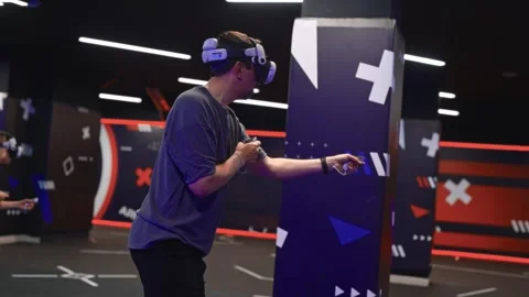 Man playing competitive VR shooter with friends at virtual reality lounge Stock-Footage 309306252