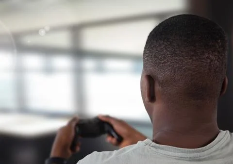 Man playing with computer game controller with bright blurred background Stock Photos