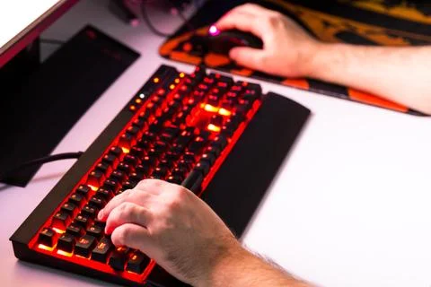 Man playing computer game on custom made desktop with joypad, keyboard, mouse Stock Photos