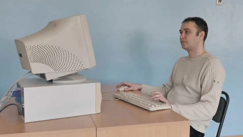 Man playing computer game on the old computer, he puts his feet on the table  Stock Footage 126085554