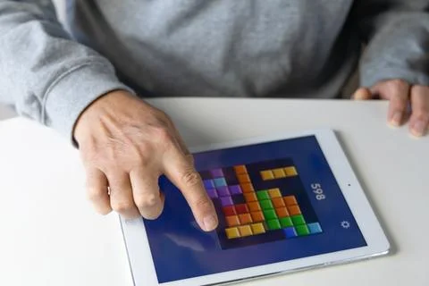A man playing the computer game Tetris on a tablet. Stock Photos