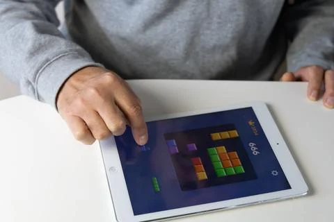 A man playing the computer game Tetris on a tablet. Stock Photos