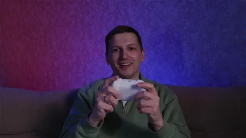 Man playing console game with flickering TV light on face Stock Footage 333757054