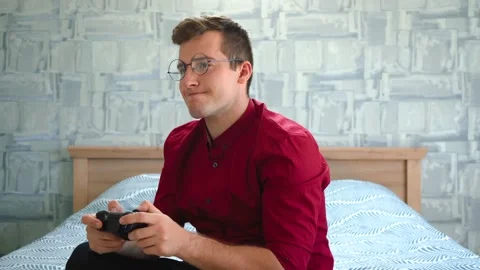A man playing a console sitting on the couch Video stock 145983089