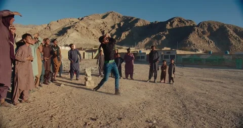 Man playing cricket with children in the mountains of Quetta, Pakistan Stock Footage 232012114