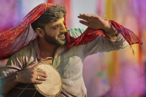 Man is playing dhol with colored face during holi color festival Stock Photos