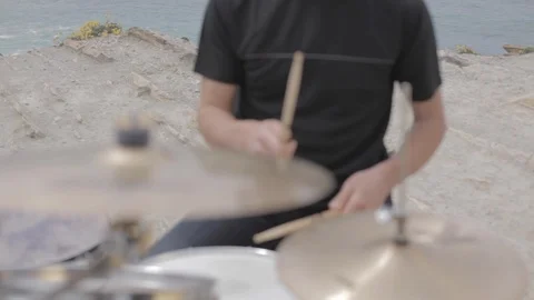 Man playing drums on top of a cliff, outdoors, by the sea in the afternoon in Stock-Footage 110914659
