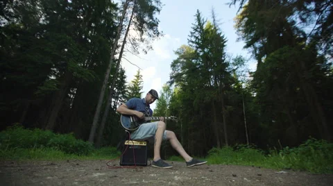 Man is playing at the electric guitar in forest Stock Footage 68353874