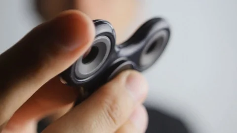 Man playing with fidget spinner. Fidget spinner is a toy which reportedly Stock Footage