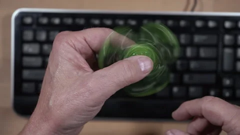 A man playing with a fidget spinner at work wasting time Stock Footage 221953649