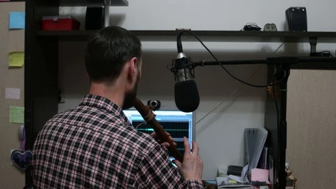 A man playing the flute in front of the computer 스톡 동영상 102554184