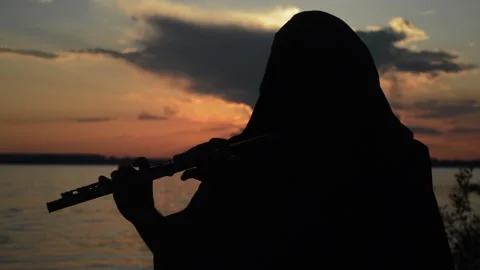 A man playing a flute at sunset Stock Footage 90541573