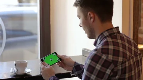 Man playing game on mobile cell phone with green touch screen in cafe. Stock Footage 73020871