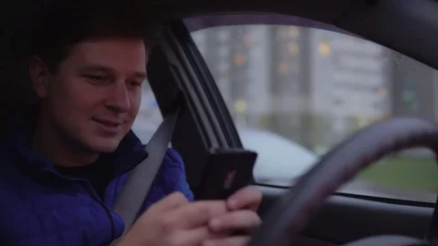 A man is playing a game on a mobile phone while driving a car. Stock Footage 81235519