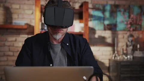 Man playing game on virtual reality googles at home with laptop computer on desk Stock Footage 148433700