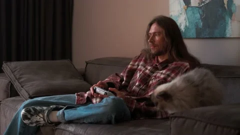 A man playing games on a console at home sitting on the couch. Stock Footage 238479507