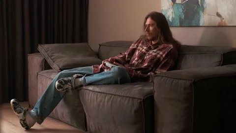 A man playing games on a console at home sitting on the couch. Video stock 238479624