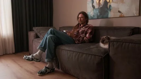 A man playing games on a console at home sitting on the couch. Stock Footage 238479803