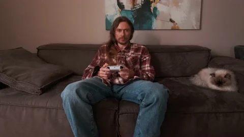 A man playing games on a console at home sitting on the couch. Stock Footage 238479855