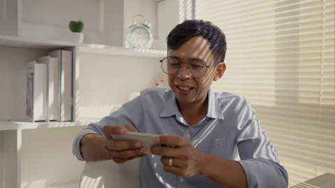 Man playing games on mobile phone with fun, Enjoy playing games on your smart Stockbeeldmateriaal 263476337