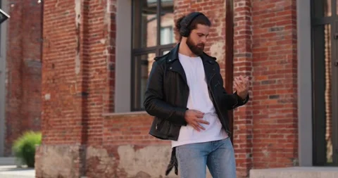 Man playing ghost guitar, using headphones while walking in the street. Video stock 246754006