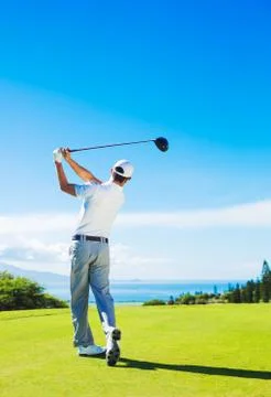 Man playing golf, hitting ball from the tee 写真素材