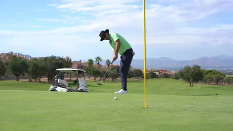 Man playing golf, putting the ball into the hole on the green with the putter Vídeo Stock 213996282