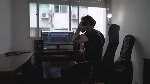 Man playing guitar and editing in a audio software, wide shot Stock Footage 146858244