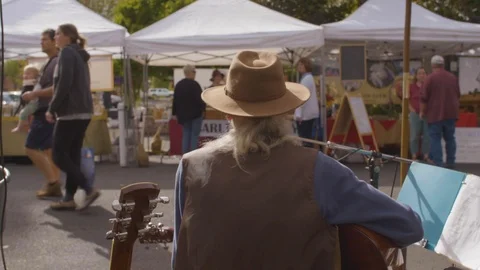 Man playing guitar and singing songs at street market Stock Footage 87804192