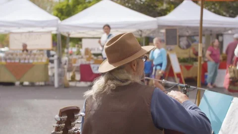 Man playing guitar and singing songs at street market Stock Footage 87804201
