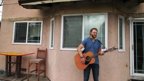 Man playing guitar in backyard Stock Footage 154762980