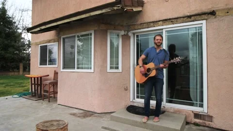 Man playing guitar in backyard Stock Footage 154763117