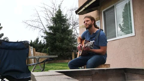 Man playing guitar in backyard Stock Footage 154763282