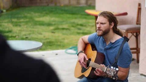 Man playing guitar in backyard Stock Footage 154763348