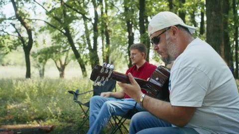 Man playing guitar in the foreground with another listening in the background in Stock Footage 264317875