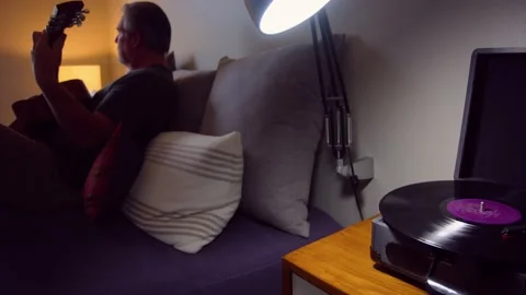 Man playing guitar at home while listening to record player Stock Footage 162931971