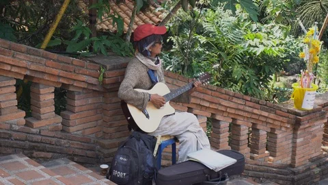 Man playing the guitar To receive donations in the temple Stock Footage 123747485