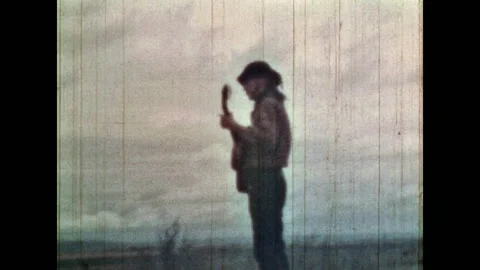 Man playing guitar, singing on cloudy sky background in wild field nature Stock Footage 279555187