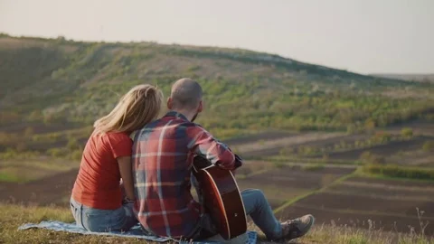 Man playing guitar surrounded by the green hills Stock Footage 75257906