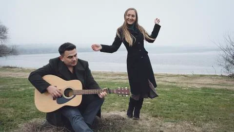 Man playing guitar while his partner is dancing Stock Photos