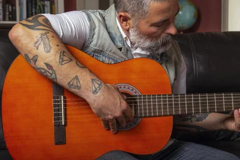 Man playing guitar while receiving online lessons. Online learning concept Stock Photos