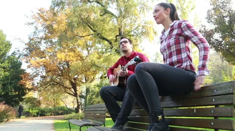 Man playing guitar while woman dancing to the rhythm, sitting next to him on Stock Footage 59557052