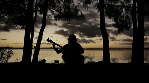 Man playing guitarin front of the Sun-set silhouette Vidéo 69260039