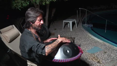 Man playing handpan near pool 24 Haziran 2026 fethiye mugla turkey Stock Footage 341529935