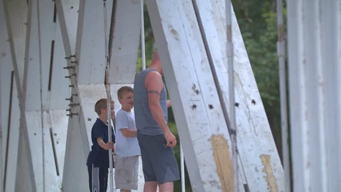 Man Playing with His Sons on a Covered Bridge Stock Footage 91592684