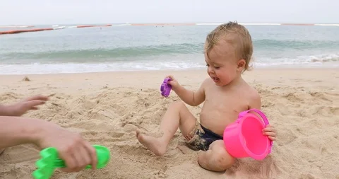 Man playing with infant in sand Stock Footage 88435070