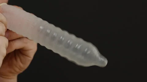 A Man Playing by Inflating a Condom Like a Balloon Against a Black Background, Stock Footage 301040056