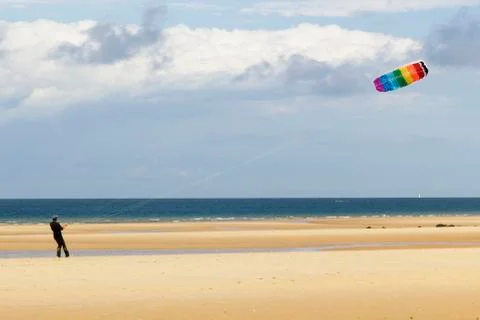 A man playing with a kite at the beach Stock Photos
