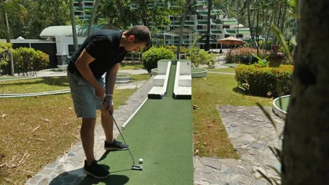 Man playing mini golf on green course during leisure activity at resort Stock Footage 268036810